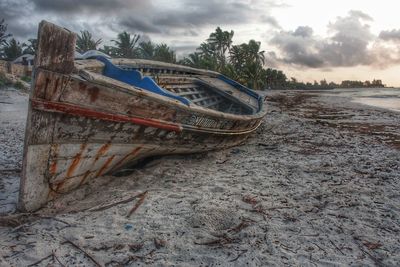 Abandoned boat moored on beach against sky