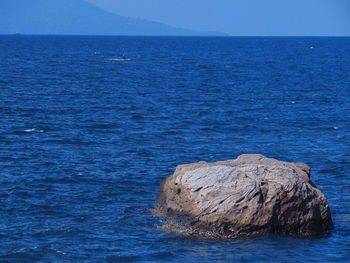 Rock formation in sea against blue sky