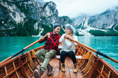 Woman sitting on a boat in lake against mountains