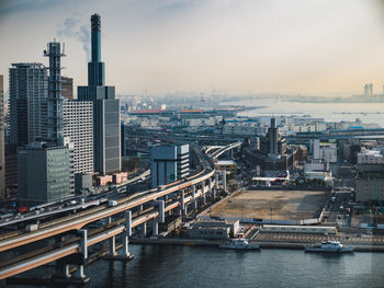 Bridge over river by buildings in city against sky