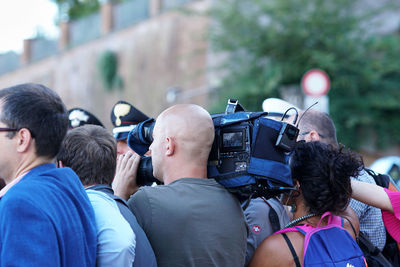 Rear view of people photographing cars on street