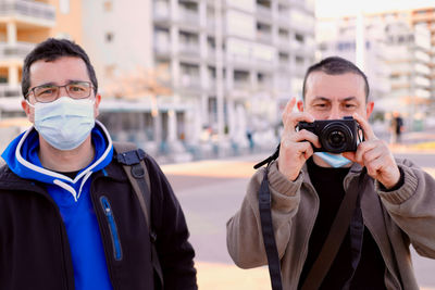 Two men taking pictures with a professional reflex camera.