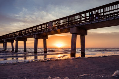 Pier over sea against sky during sunset