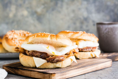 Bagels with fried meat, poached egg and cheese on a board on the table. homemade fast food