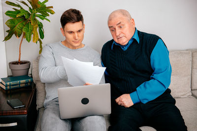Happy man showing documents to grandfather at home