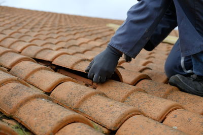 Low section of man repairing roof tiles