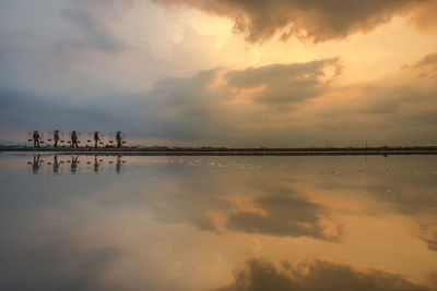 Scenic reflection view of salt making field against sky during sunrise