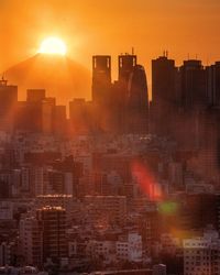 Modern buildings in city against sky during sunset