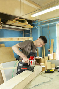 Stapling of wooden parts with a red pneumatic stapler. furniture manufacture. vertical format.