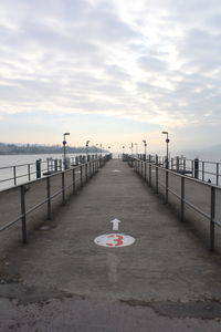 Markings on pier over river against cloudy sky