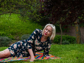 Mature woman lying on picnic blanket at park