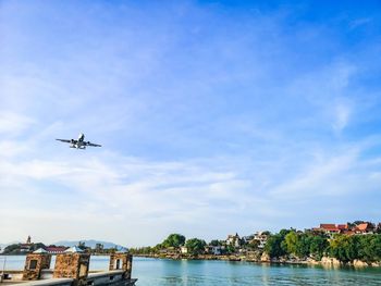 Airplane flying over river against sky