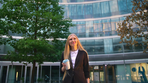 Portrait of young woman standing in city