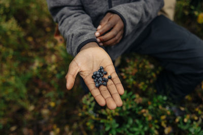 Boy showing fresh blueberries on palm in forest during vacation