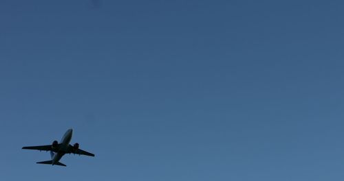 Low angle view of airplane against clear blue sky