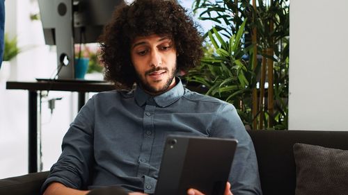 Portrait of young woman using digital tablet while sitting at home