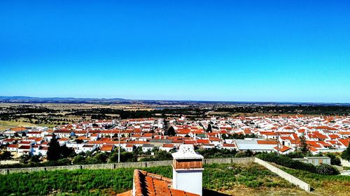 Houses in town against clear blue sky