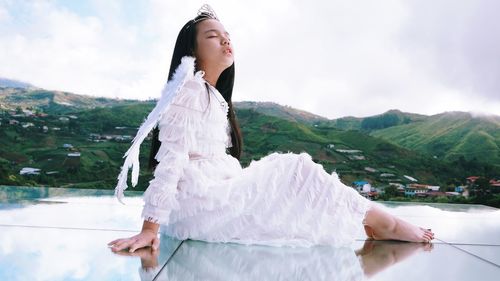 Young woman standing on mountain against sky