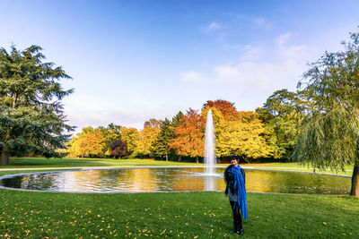 Full length portrait of woman standing by fountain at park