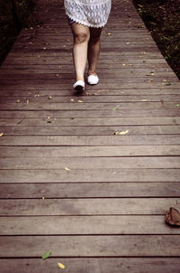 Low section of woman walking on wooden floor
