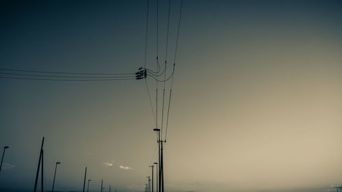 Low angle view of electricity pylon against sky during sunset