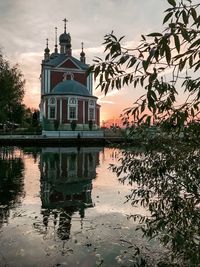Reflection of building on lake against sky during sunset
