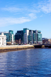 Sea by buildings against blue sky