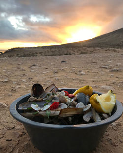 Fruits on sand at beach against sky during sunset