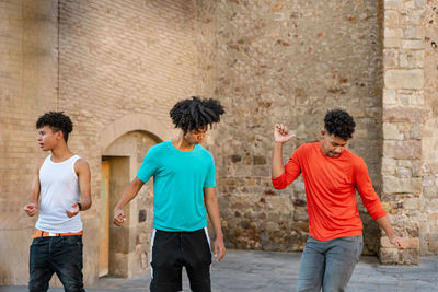 Friends dancing against wall