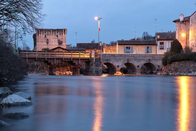 Bridge over river against sky in city