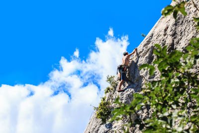 Low angle view of man on cliff against blue sky