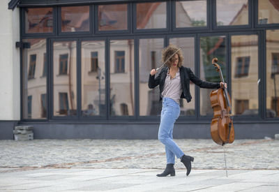 Full length of woman playing violin while standing on street