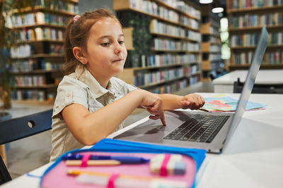 Positively engaged student doing her homework using laptop at primary school. back to school