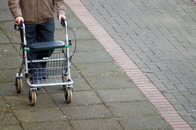 Low section of man with wheelchair walking on road