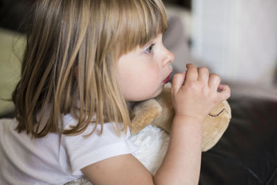 Close-up of girl with toy looking away at home