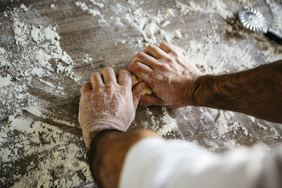 Cropped hands of man preparing dough on table