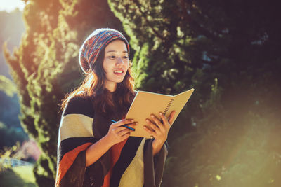 Woman reading book while standing on land