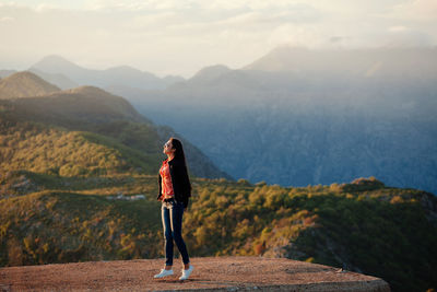 Woman standing on retaining wall against mountains