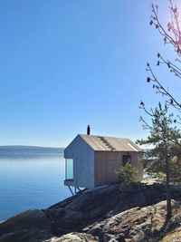 Sauna house by sea against clear blue sky