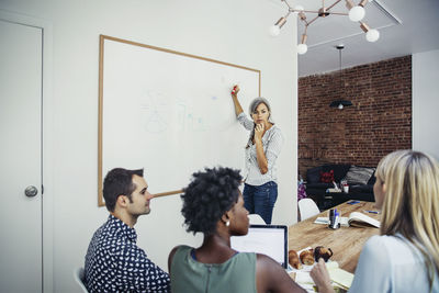 Mature businesswoman giving presentation to executives in creative office