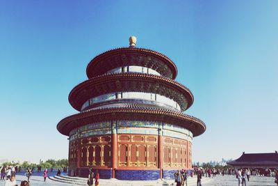 Low angle view of tourists against clear blue sky