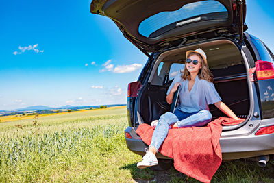 Full length of woman sitting on field against sky