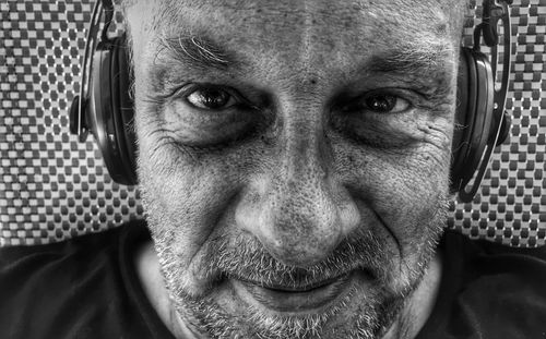 Close-up portrait of man wearing headphones by wall