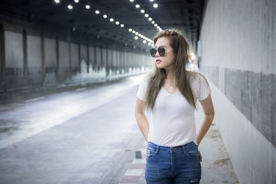 Portrait of young woman standing against wall