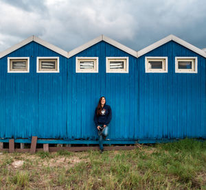 Portrait of young woman standing against building