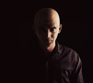 Portrait of young man standing against black background