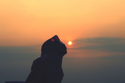 Silhouette woman kissing sun against sky during sunset