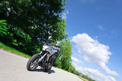 Man riding motorcycle on road against sky