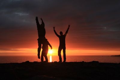 Silhouette of celebrating friends against sky during islandic midnight sun