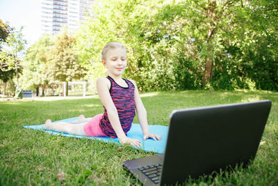 Caucasian girl child doing sport workout outdoor online. video yoga stretching on internet. 